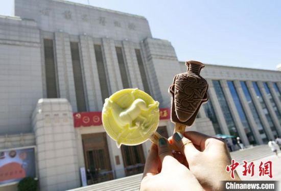 2021年7月30日，游客手拿“銅奔馬”“彩陶瓶”造型的雪糕，在甘肅省博物館前拍照打卡?！「哒?攝