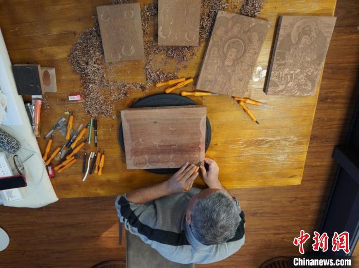 圖為徐晉林正在梨木木板上雕刻敦煌壁畫(huà)?！【琶赖┰?　攝