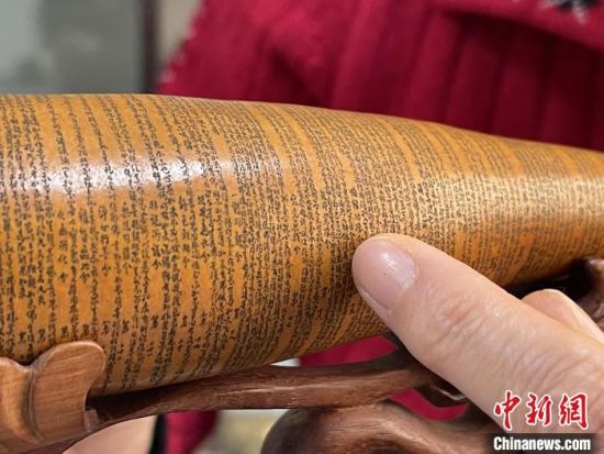 圖為長(zhǎng)約二十公分的長(zhǎng)條葫蘆雕刻佛教經(jīng)文作品?！堟?攝