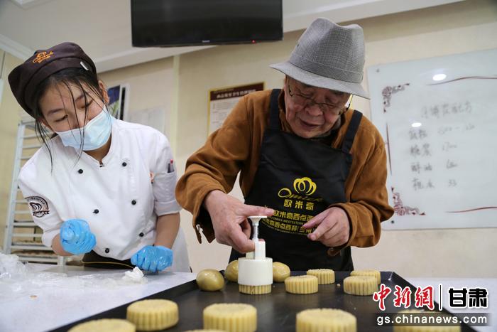 當日，受邀參加活動的臺胞臺屬代表、兩岸婚姻及子女、在甘臺商代表等歡聚一堂。圖為77歲的在甘臺胞潘天鑒制作月餅。九美旦增 攝