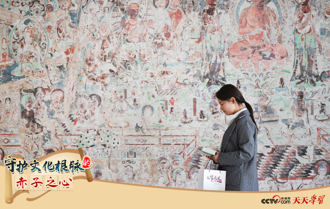 2023年4月25日，敦煌研究院文物數(shù)字化保護團隊創(chuàng)意營銷人員廖雪婷從一幅高保真復(fù)制壁畫前走過。